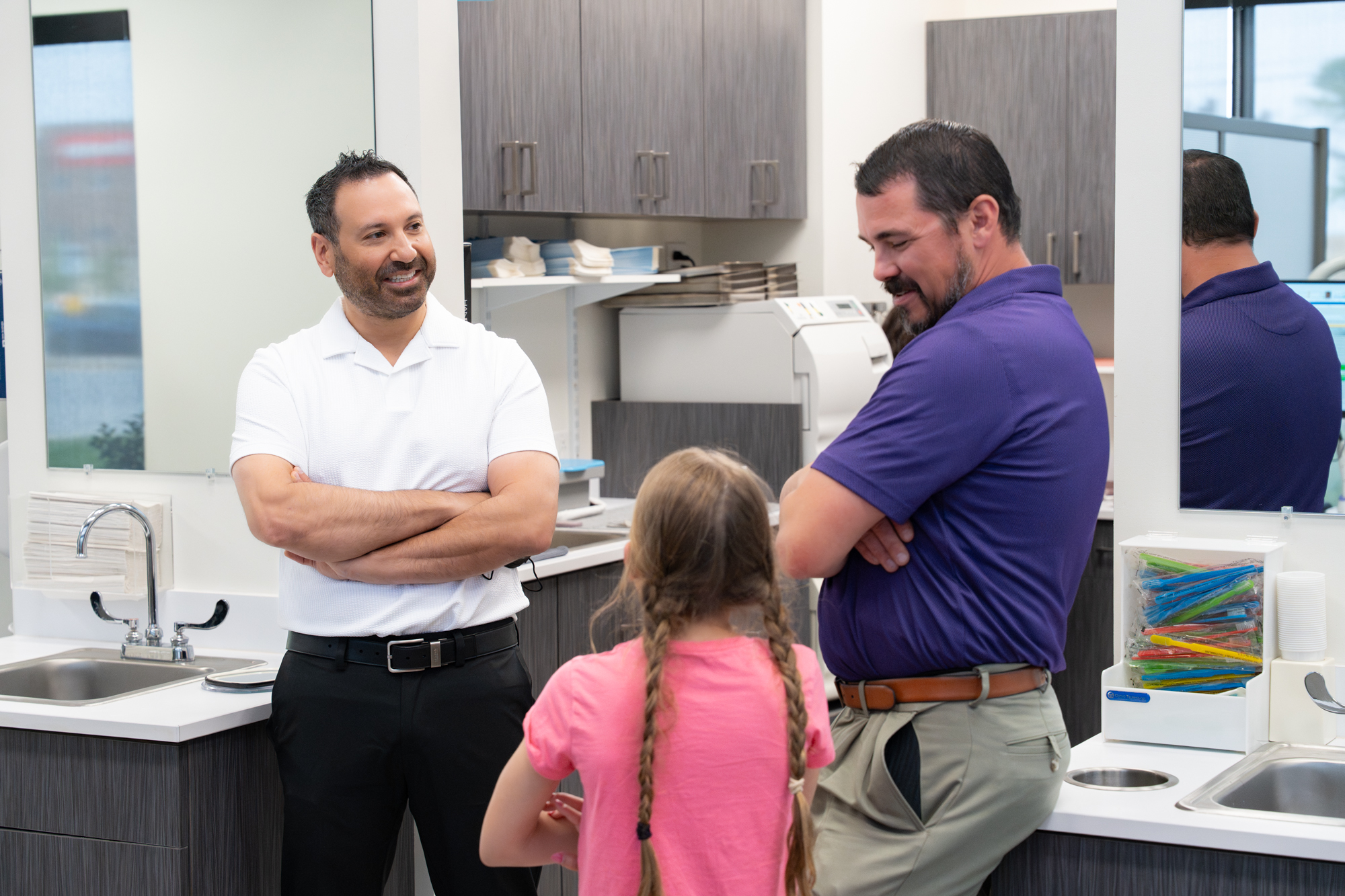 Dr. Ravi Rajanna and Lakewood Orthodontics team interacting with a family, braces and clear aligners visible in the background.