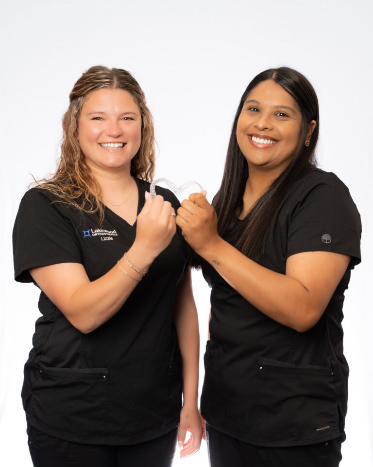 Lakewood Orthodontics team members holding clear aligners in Lee's Summit, MO